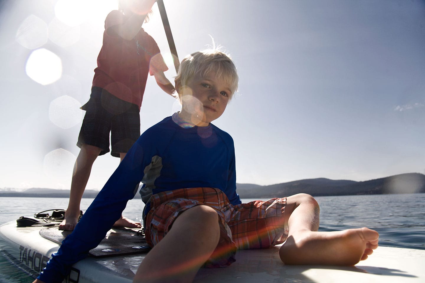little boy sitting on a paddle board in lake tahoe