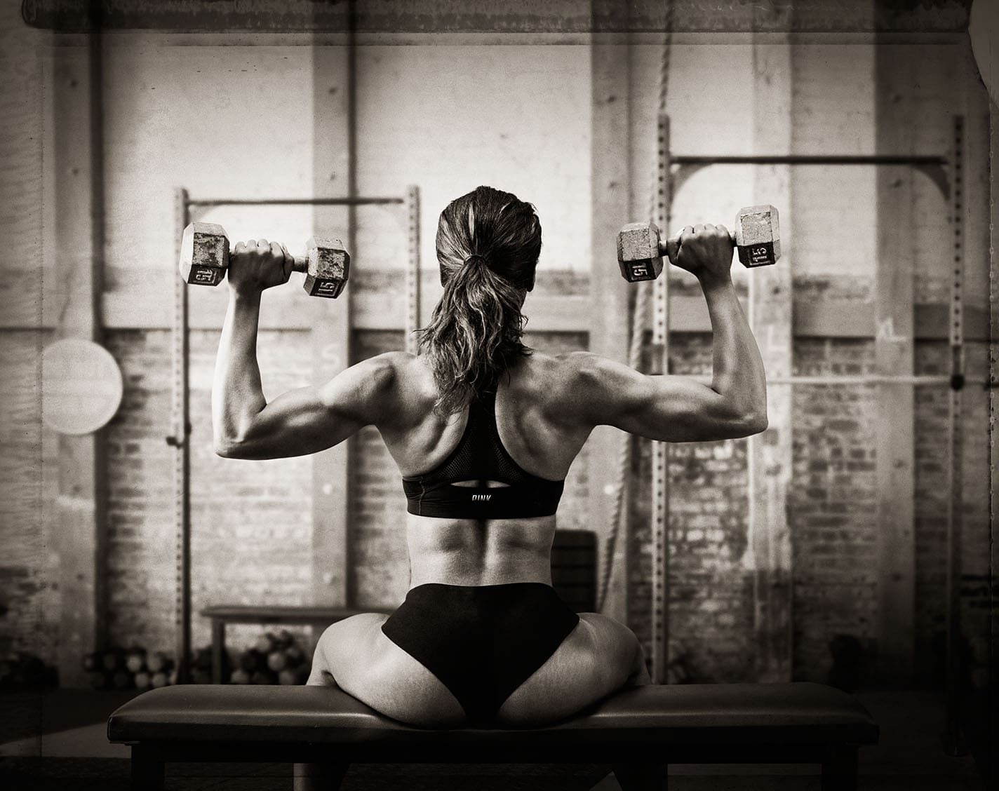 Black and White Image Behind Athlete Nicole Harris Doing Shoulder Press Two Piece Workout Apparel Chanel