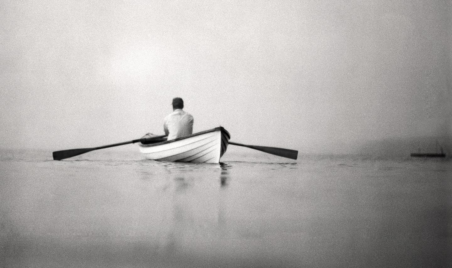 Black and White Image of Man Canoeing