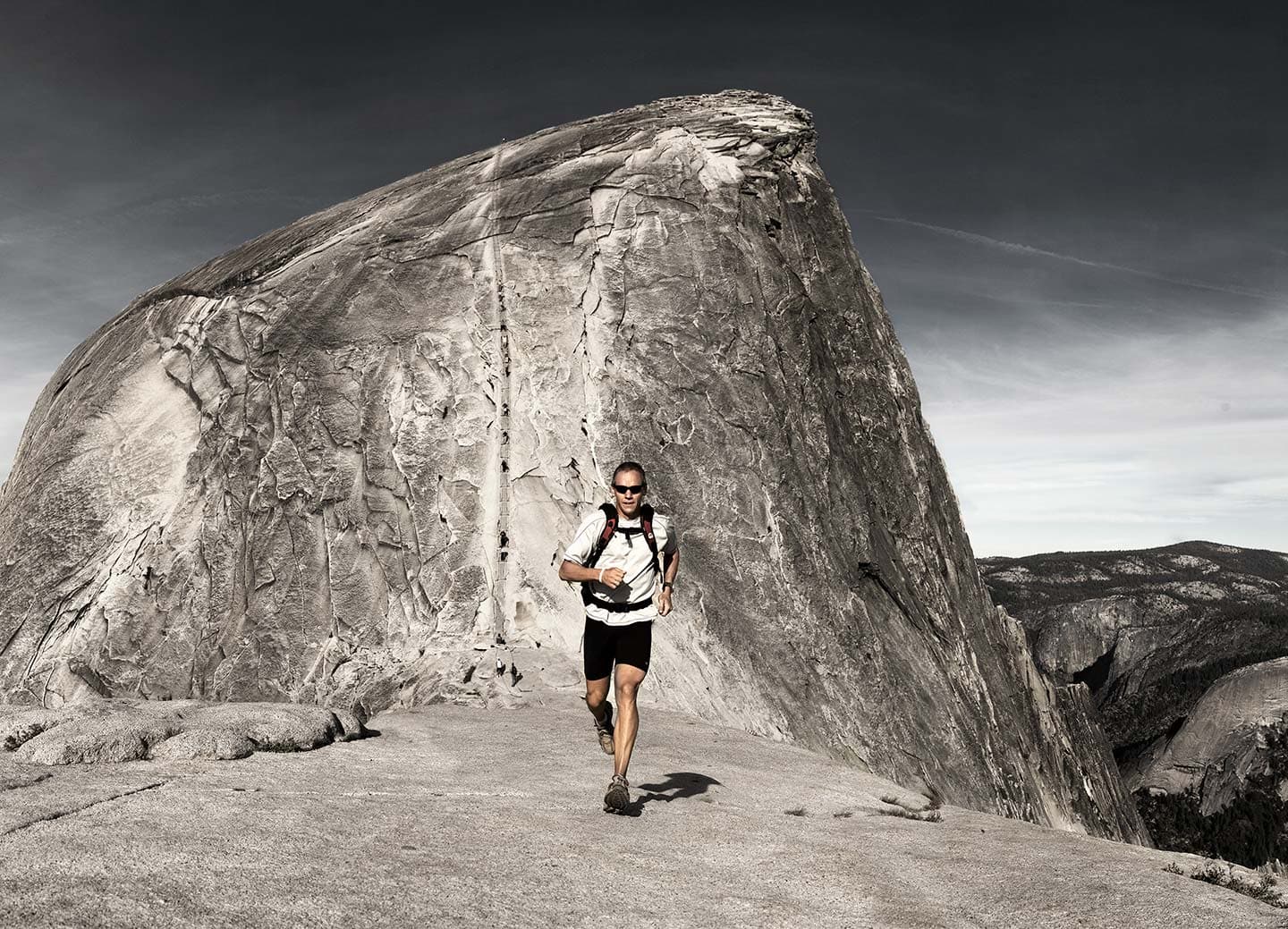 Image of Man in Black and White Sports Apparel Running with Grey Cliff in Background