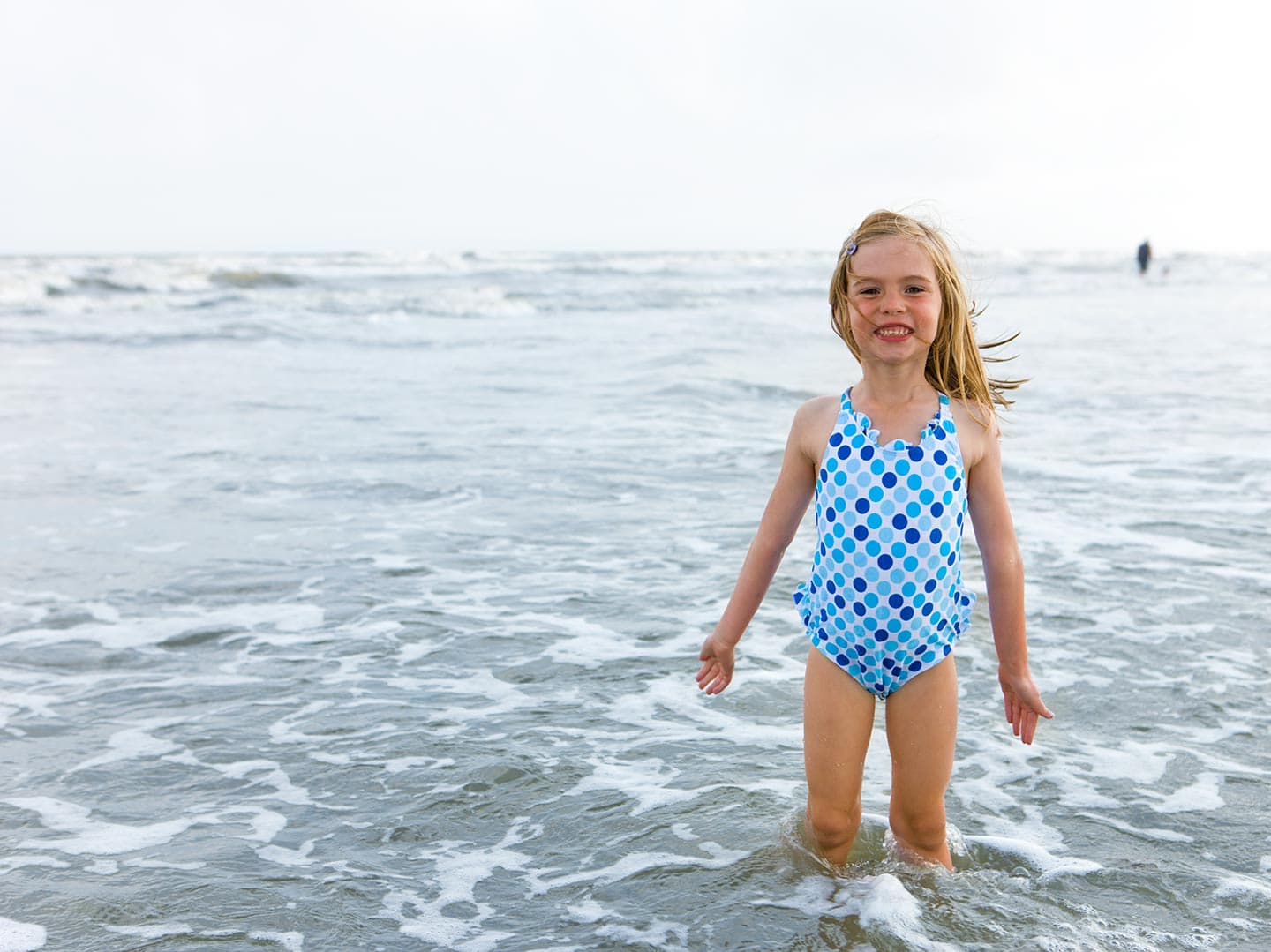 Little Girl at Beach in Swimsuit Smiling in Water