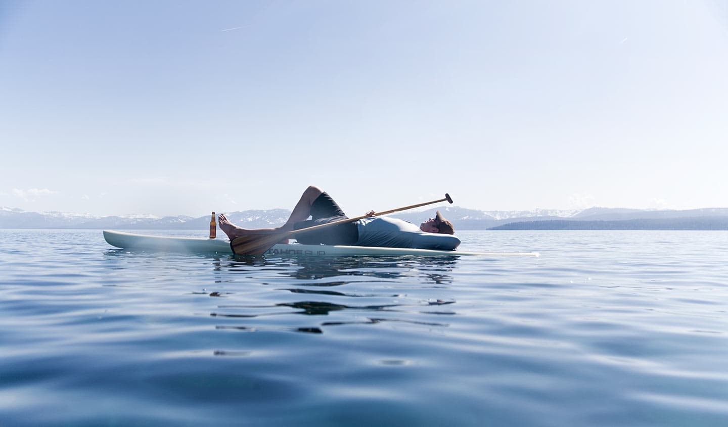 Man Relaxing Lying Down Kayak on Blue Water