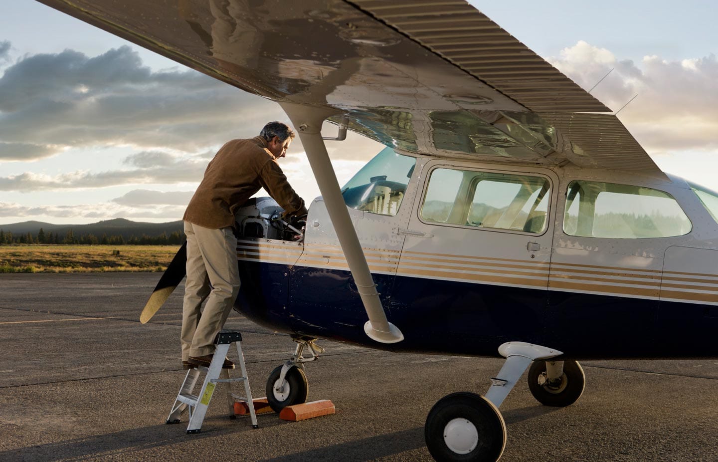Man on Step Stool Fixing Private Plane