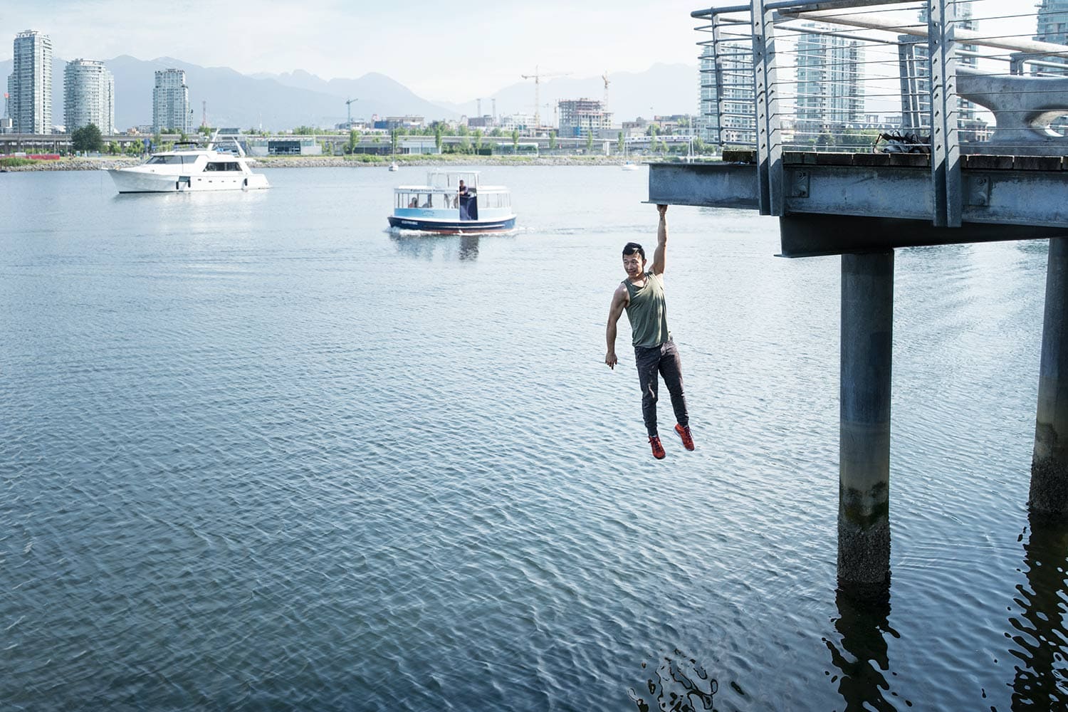 Parkour-male-Athlete-hanging-over-water-from-a-bridge-Rod-McLean