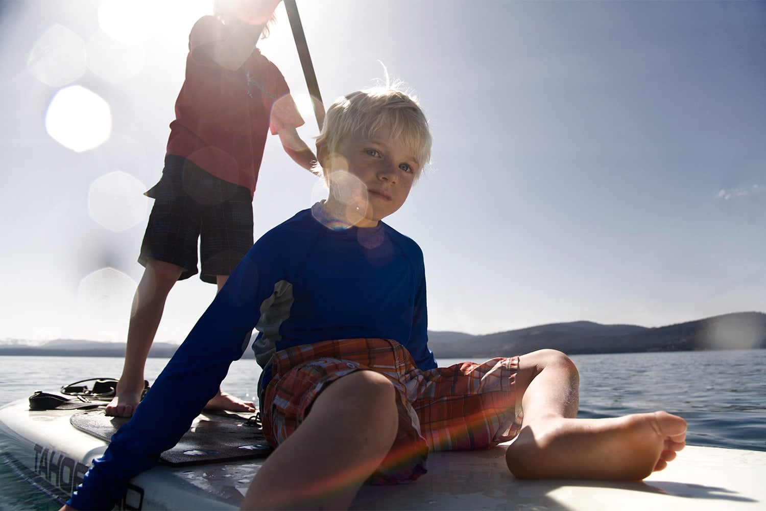 little-boy-sitting-on-a-paddle-board-in-lake-tahoe-Rod-Mclean