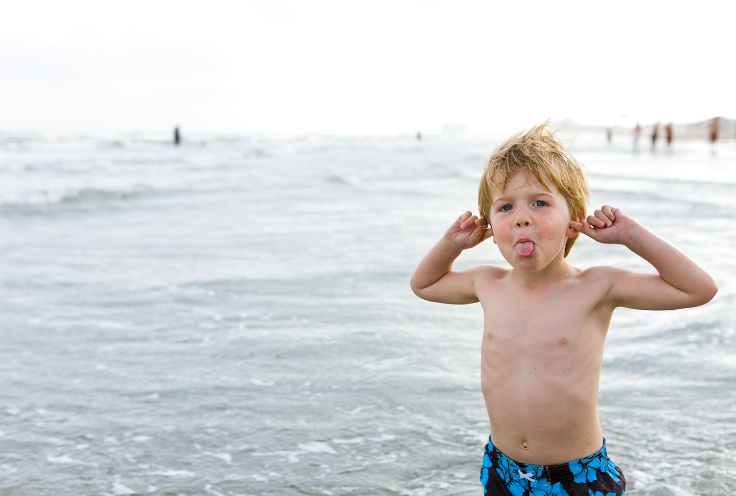 Little Boy at Beach in Swimsuit Making Silly Face